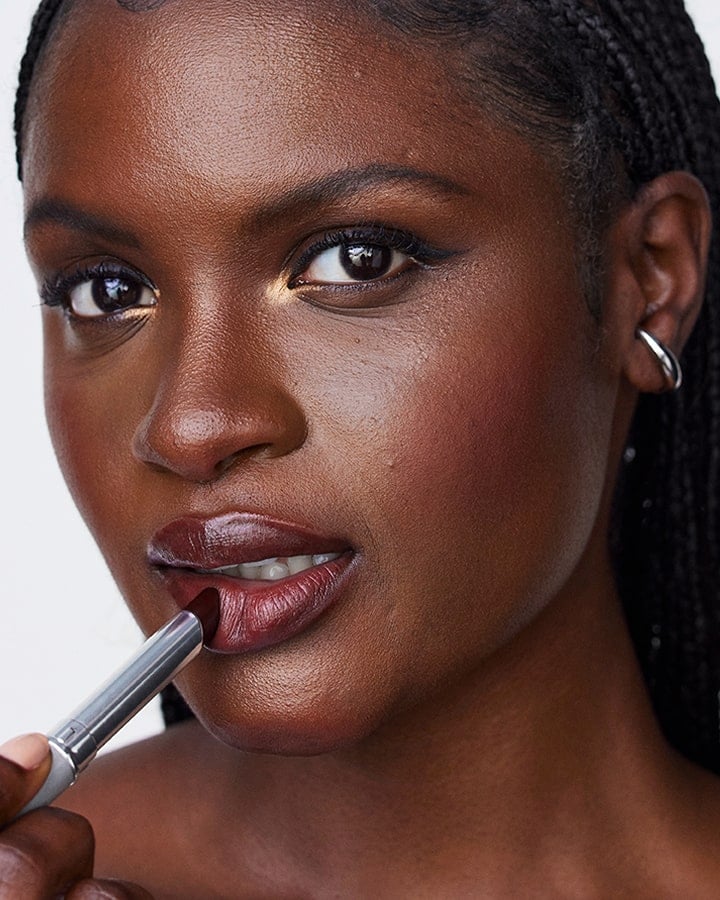 A close up shot of a model putting on a black honey lipstick 