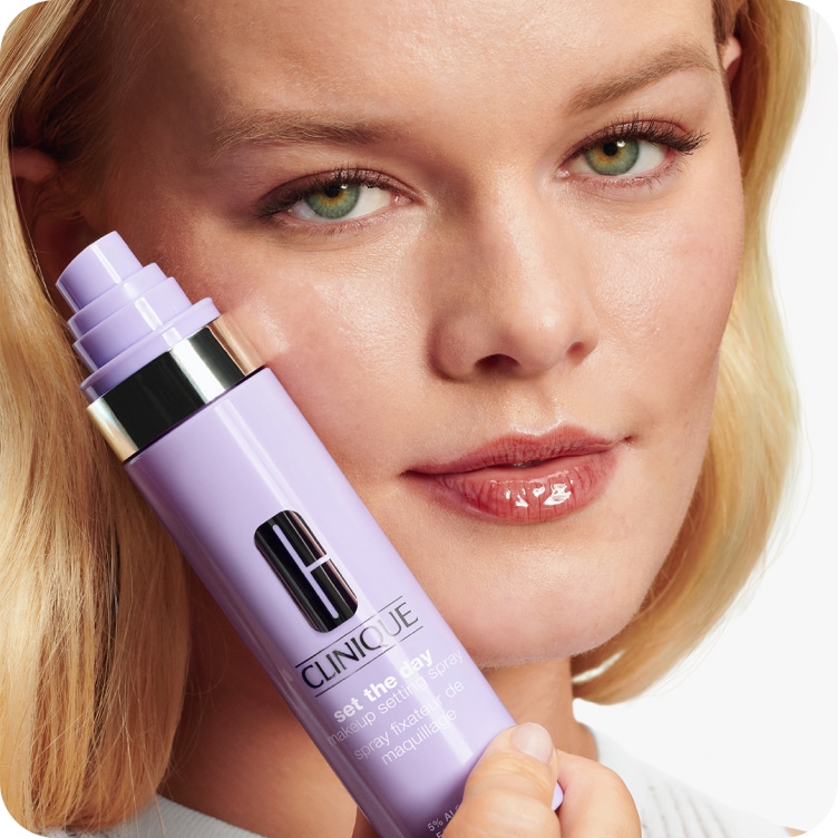 Model holding up Clinique setting spray to the left of her face.